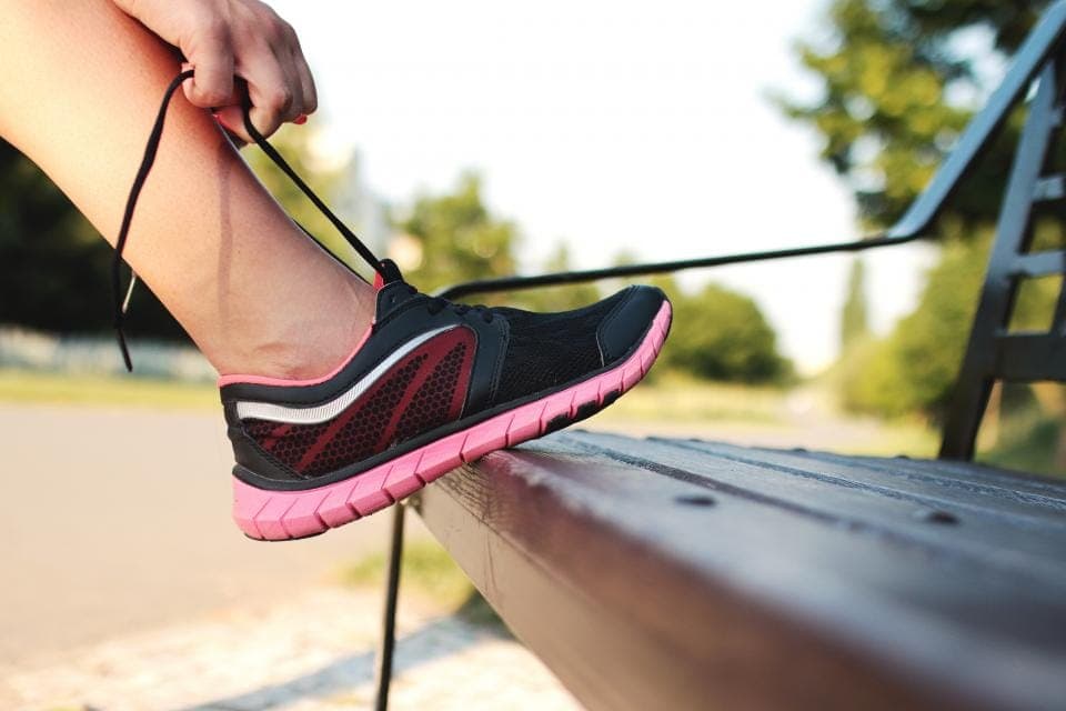 A lightweight mesh road-running shoe photographed on asphalt